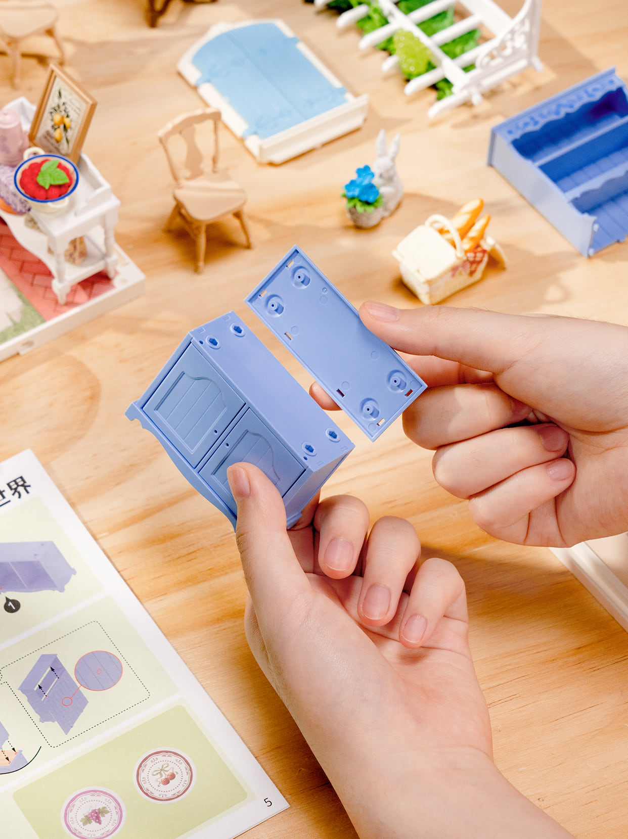 Hands assembling a blue cabinet for a miniature room